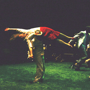 Escena do espectáculo Illa Reunión, na que un home sostén a unha muller sobre un dos seus ombreiros.