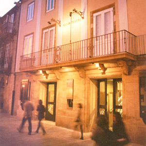 Fotografía da fachada do Salón Teatro, un inmoble de pedra, de baixo e dous andares cun balcón de ferro.